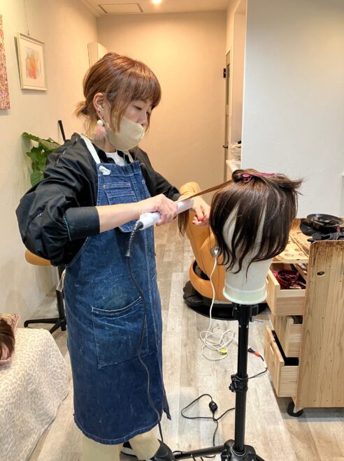 ウィッグを仕上げる美容師
